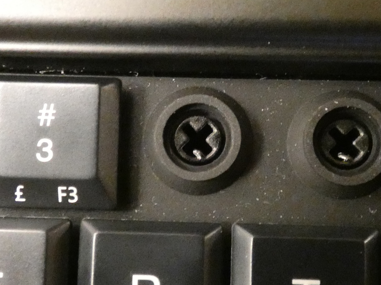 A close-up photo of the keyboard itself where the keycap is missing. Theres an x-shaped hole in the middle, surrounded by the larger and wider membrane that looks like a circle-shaped dyke. This membrane ring is pressed down by the keycap while typing.